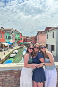 Three women hugging above a canal