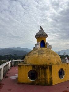 An art installation with octagonal holes in front of a mountainous horizon.