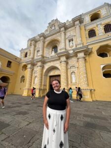 Stephanie standing in front of a yellow pillared building.