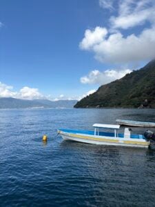 A small boat docked in the water with mountains in the background.