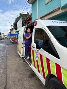 Stephanie in purple scrubs standing in the doorway of a medical van and smiling at the camera.