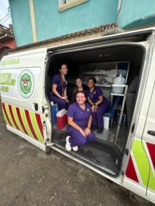 Stephanie and three other students in purple scrubs sitting in a medical van and smiling at the camera.
