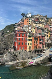 A vibrant village with colorful buildings along the shore of a tranquil body of water. 