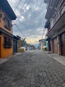 A street showing various buildings along each side and the sunset at the end.