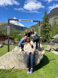 Natalia and three other students sitting on a rock and posing in front of the Matterhorn.