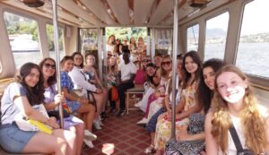 The group of students sitting in a trolley cart and smiling at the camera.