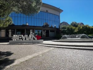 A large building with full glass windows and an art installation with #Evian and a heart.