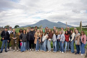Spring 25 group in Pompeii with Mount Vesuvius behind them